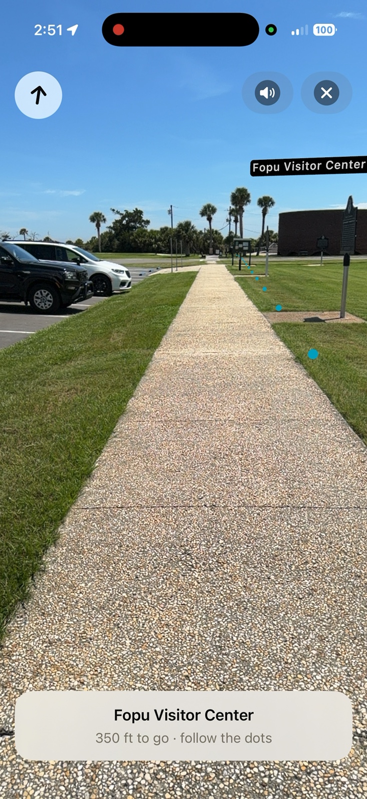 iPhone screenshot of Lookabout's AR walking guide on a path at Fort Pulaski: teal breadcrumb dots on the grass, a floating Fopu Visitor Center label, and a banner reading 300 ft to go, follow the dots.