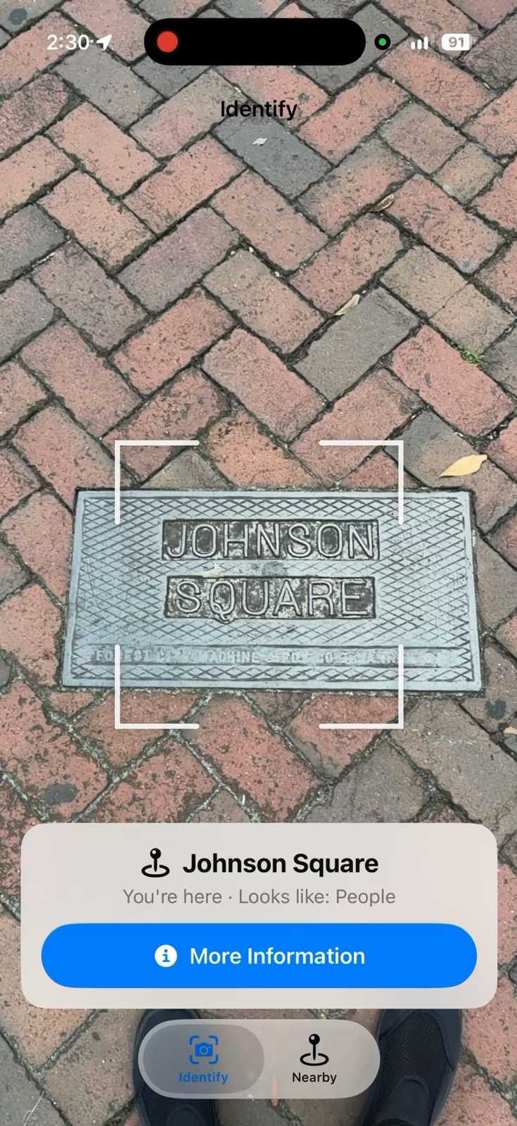iPhone screenshot of Lookabout aimed at the Johnson Square ground plaque set in brick pavers, with an identify card reading “Johnson Square — You’re here” and a More Information button.